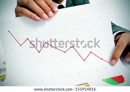 man wearing a suit sitting in a table showing a graph of economic losses