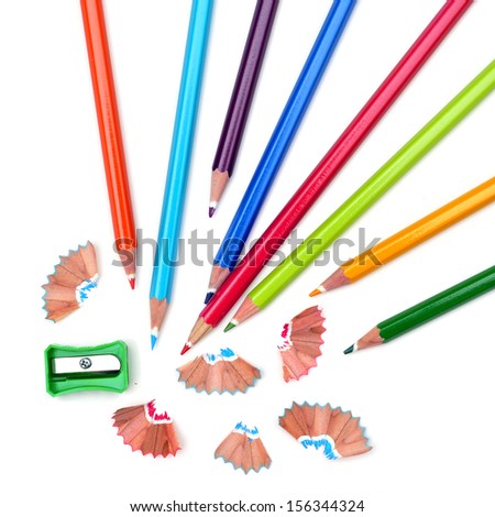 some colored pencils of different colors and a pencil sharpener and pencil shavings on a white background