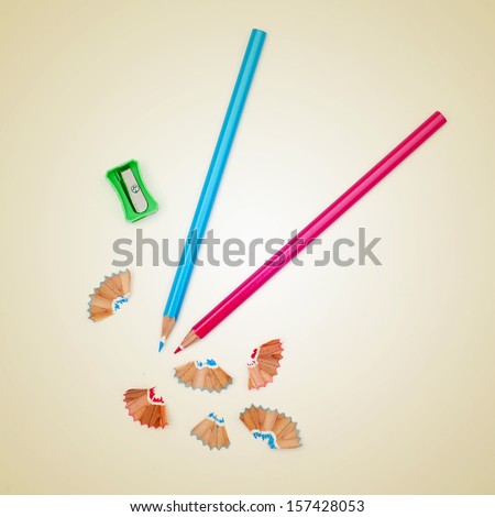 picture of some colored pencils and a pencil sharpener on a beige background, with a retro effect