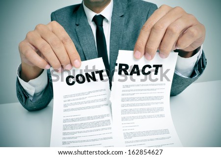 Man Wearing A Suit Sitting In A Table Ripping Up A Contract