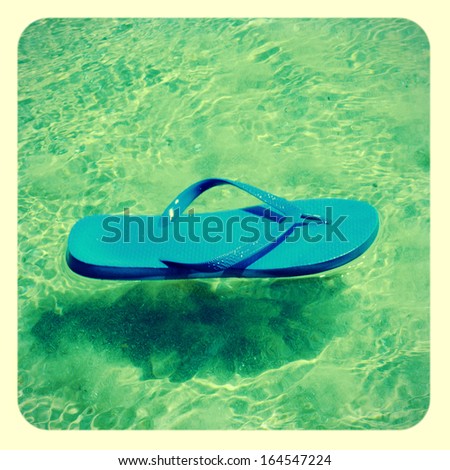 picture of a blue flip-flop on the seawater in the summer, with a retro effect