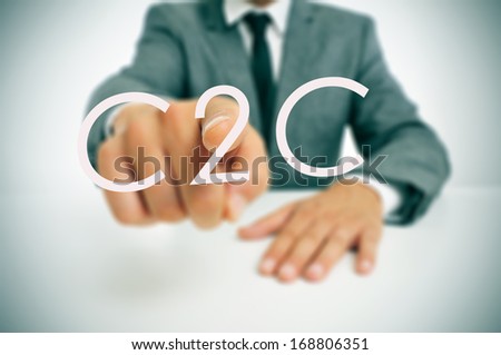 man wearing a suit sitting in a table pointing to the word C2C, consumer-to-consumer, written in the foreground