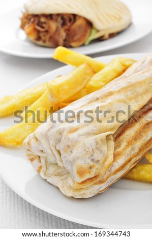 closeup of a durum kebab with fries and a doner kebab in the background on a set table