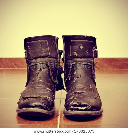 picture of a pair of worn and torn boots on the floor with a retro effect