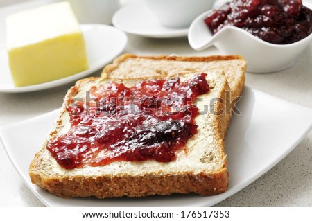 closeup with a plate with some toasts with butter and fig jam on a table, with a cup of coffee in the background