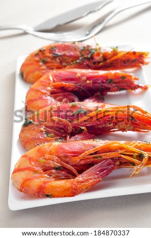 closeup of a plate with spanish shrimps cooked with garlic and parsley on a set table