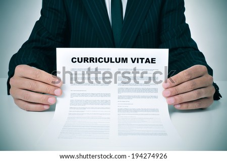 a man wearing a suit showing his curriculum vitae