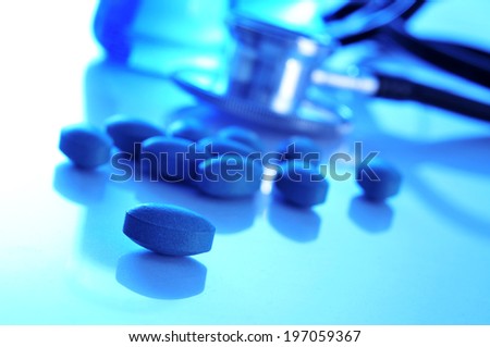 closeup of the desk of a doctors office with pills, a stethoscope and some flasks