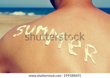 the word summer written with sunblock on the back of a man who is sunbathing on the beach