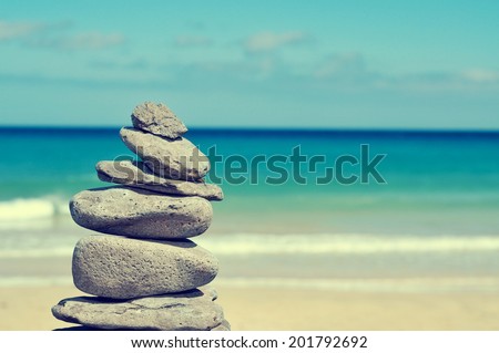 stack of balanced stones in a white sand beach, with a cross-processed effect