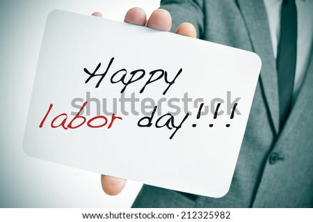 a man wearing a suit showing a signboard with the text happy labor day written in it