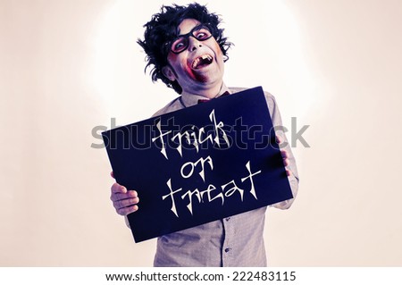 a gap-toothed zombie showing a black signboard with the text trick or treat written in it, with a retro effect