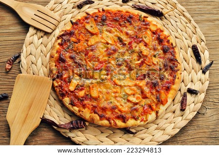 a pizza with chicken, red pepper and green pepper, served on a wooden background