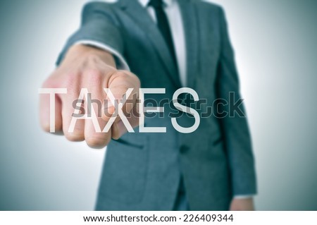 man wearing a suit pointing the finger to the word taxes written in the foreground