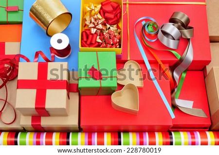 a pile of different boxes, wrapping paper, ribbon and ribbon bows of different colors to prepare gifts