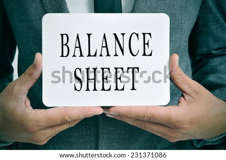 a businessman showing a signboard with the text balance sheet written in it