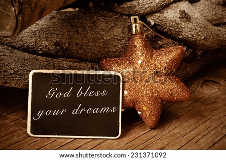 the text god bless your dreams written in a blackboard and a christmas star and a pile of logs in the background