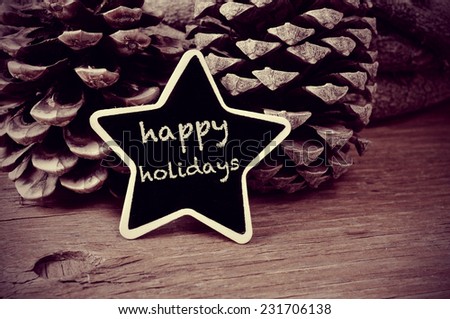 the text happy holidays written in a star-shaped blackboard and some pinecones on a rustic wooden table, in black and white