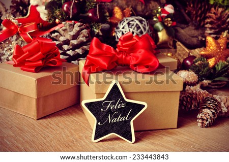 a star-shaped chalkboard with the text feliz natal, merry christmas in portuguese, on a rustic wooden table full of gifts and christmas ornaments, such christmas stars and pine cones