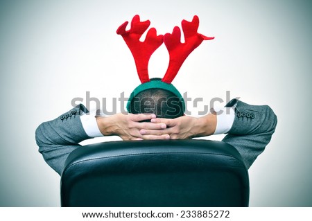 a man with a reindeer antlers headband relaxing in his office chair after an office christmas party