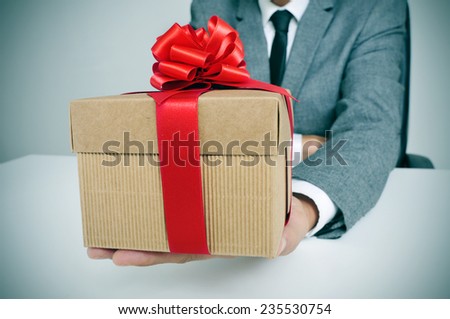 man in suit sitting in his office holding a gift with a red ribbon