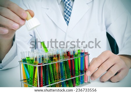 man in white coat with test tubes with liquids of different colors in a laboratory