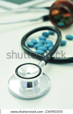 closeup of the desk of a doctors office with a stethoscope and a bottle with pills