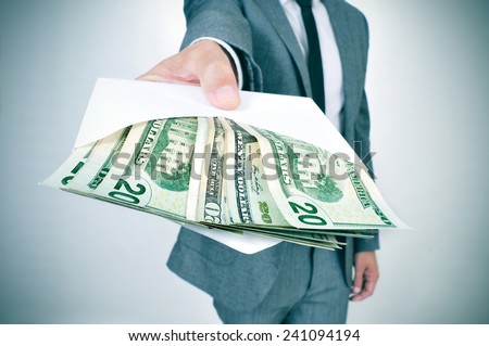 a man in suit giving an envelope full of american dollar bills