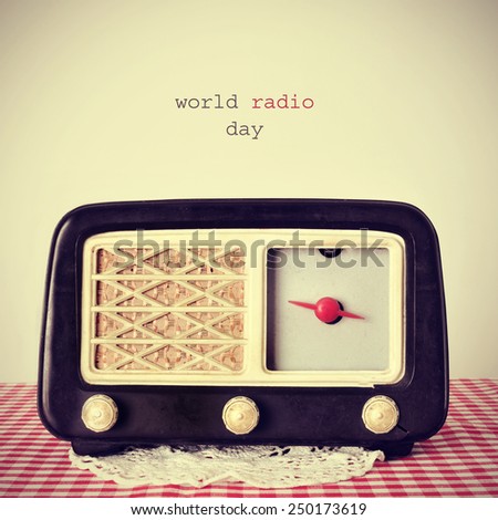 the text world radio day and an antique radio receptor on a table covered with a red and white checkered tablecloth, with a retro effect