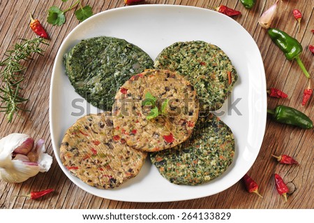 some different raw veggie burgers in a plate on a rustic wooden table