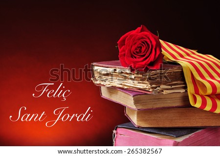 a red rose and the catalan flag on a pile of old books and the text Felic Sant Jordi, Happy Saint Georges Day, written in catalan, when it is tradition to give red roses and books in Catalonia, Spain
