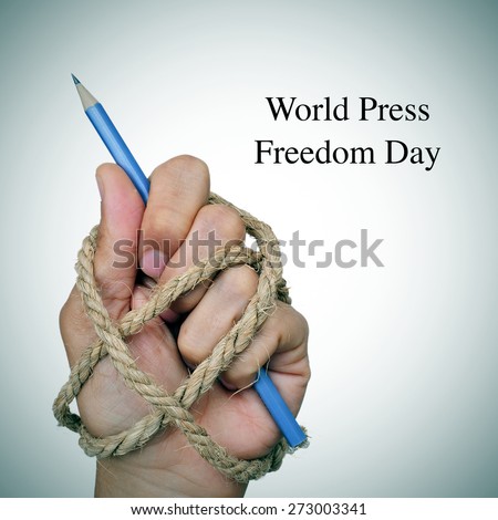 the text world press freedom day and the hand of a man, completely tied with rope, holding a pencil, depicting the idea of oppression or repression