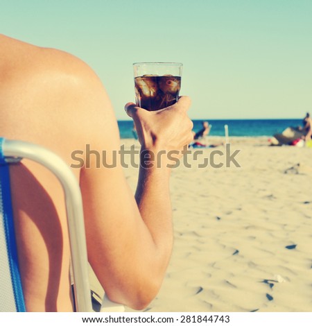 a young caucasian man hanging out on the beach with a glass with cola drink, with a filter effect