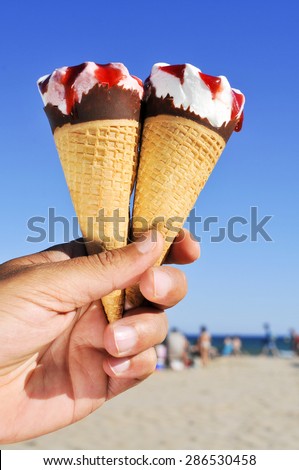 closeup of a young caucasian man with some ice cream cones of different flavors in his hand on the beach