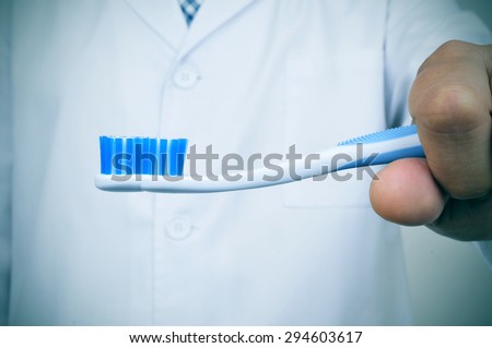a dentist showing a toothbrush depicting the importance of tooth brushing for a good oral hygiene