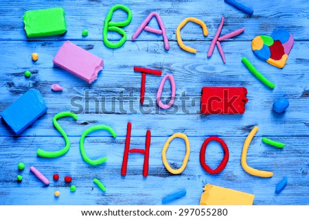 the sentence back to school written with modelling clay of different colors on a blue rustic wooden background