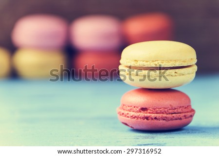 some appetizing macarons with different colors and flavors on a blue rustic wooden surface, cross processed