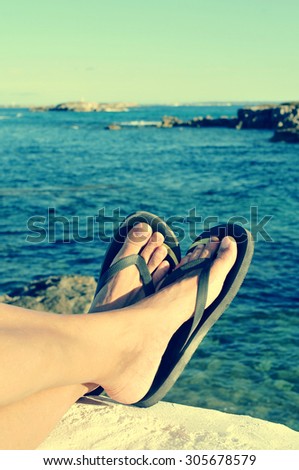 closeup of the feet of a man with flip-flops who is relaxing near the ocean in the summer, filtered