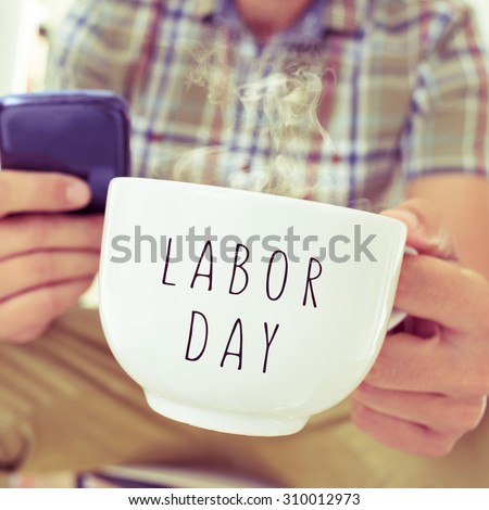 closeup of a young caucasian man with a smartphone and a mug with the text labor day