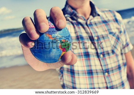 closeup of a young caucasian man with a world globe in his hand
