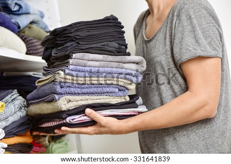 closeup of a young man carrying a pile of different folded clothes