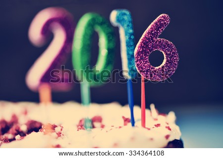 closeup of four glittering numbers of different colors forming the number 2016, as the new year, topping a cake