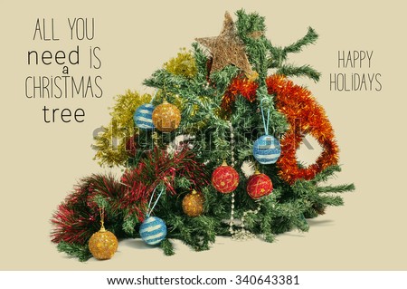 a broken christmas tree ornamented with tinsel, baubles and a star, and the text all you need is a christmas tree and happy holidays