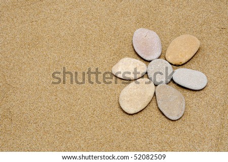 flower made with stones on a sand background