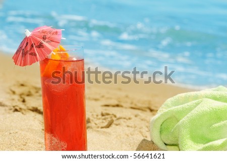 a cocktail and a towel on the sand of a beach