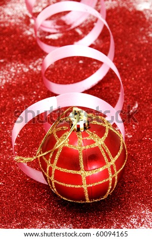 red and golden christmas ball with a pink ribbon in a red glitter background