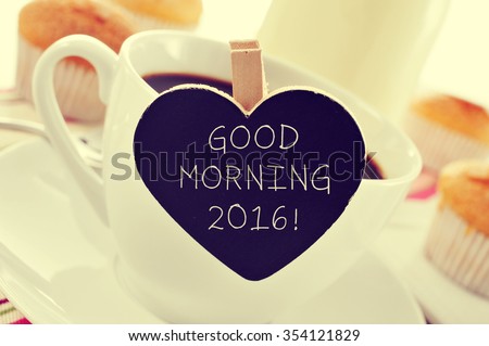 closeup of a porcelain cup of coffee with a heart-shaped signboard with the text good morning 2016 on a set table for breakfast