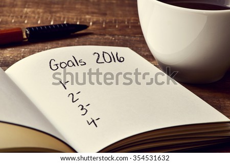 closeup of a notebook with a blank list of goals for 2016 and a cup of coffee on a rustic wooden table