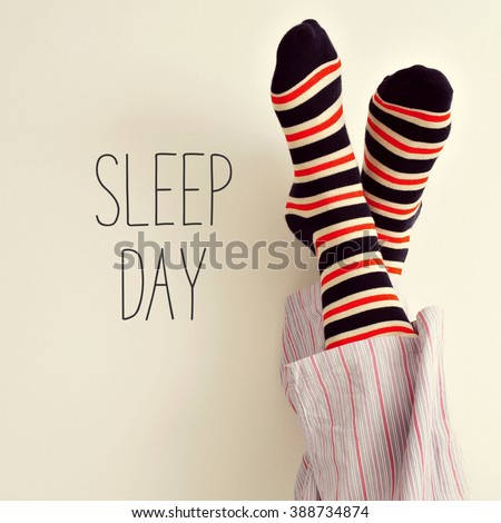closeup of a young man in pajamas wearing colorful striped socks with his feet against the wall and the text sleep day