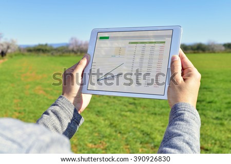 closeup of a young farmer observing some charts in a tablet computer in a fallow field
